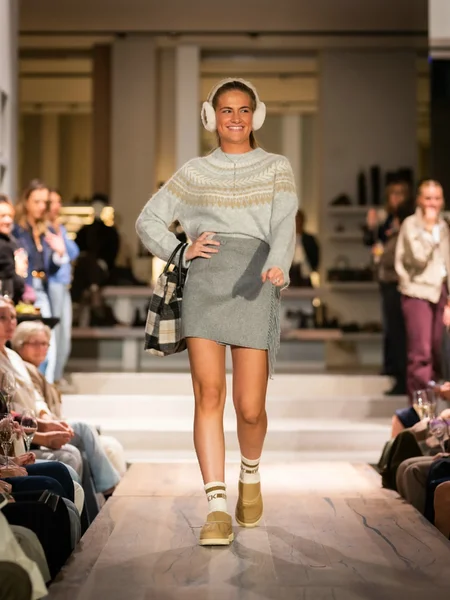 Grijze gebreide trui met korte rok, witte oorwarmers en beige boots