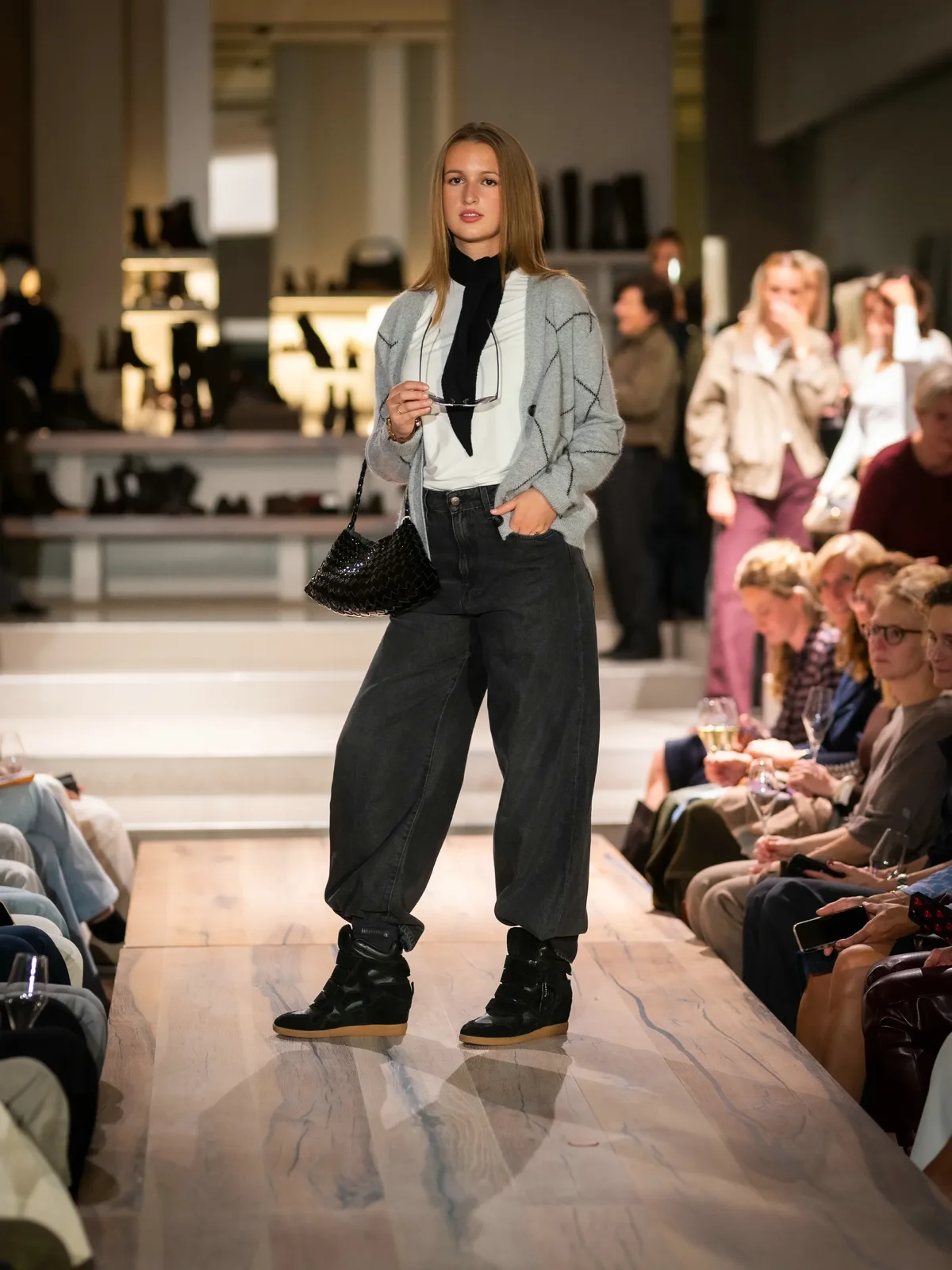 Grijze trui met wit T-shirt, zwarte broek en zwarte sneakers
