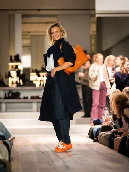 Blauwe jas met off-white blouse, blauwe broek en oranje sneakers