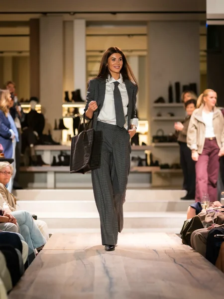 Grijze blazer met witte blouse, grijze broek en blauwe boots